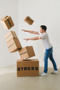 Frustrated man throwing boxes with labels like: stress, work, anxiety